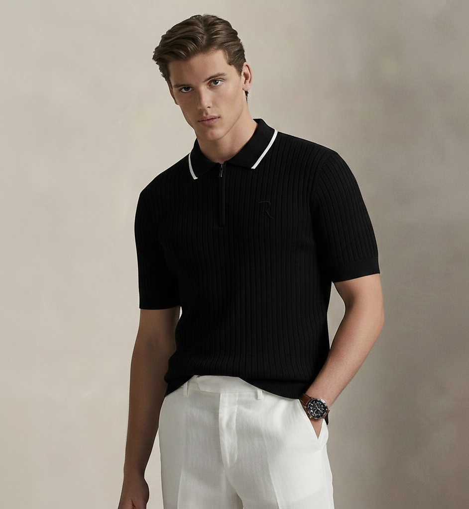 Man wearing a black ribbed polo shirt and white pants against a beige background